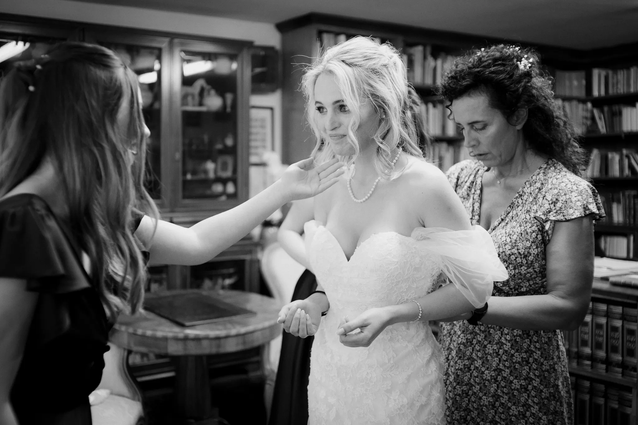 sposa emozionata. mentre sta finendo di indossare l'abito del matrimonio. Il servizio fotografico di matrimonio in bianco e nero.